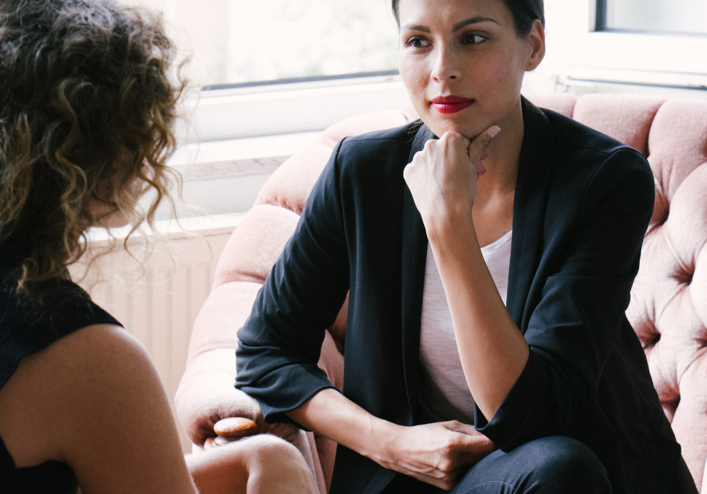 A coach and a client siting opposite each other in a coaching session